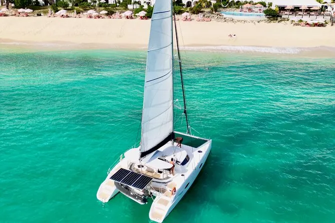 Aerial view of a catamaran sailing over turquoise water near a Caribbean island